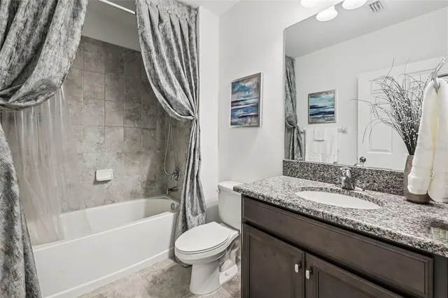 a bathroom with a granite countertop sink toilet mirror and bathtub