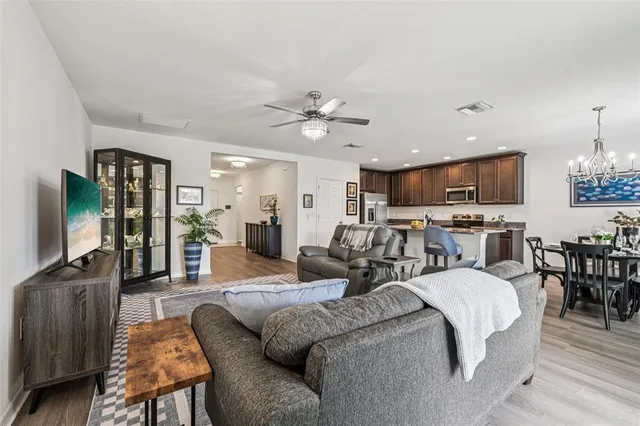 a living room with furniture kitchen view and a chandelier