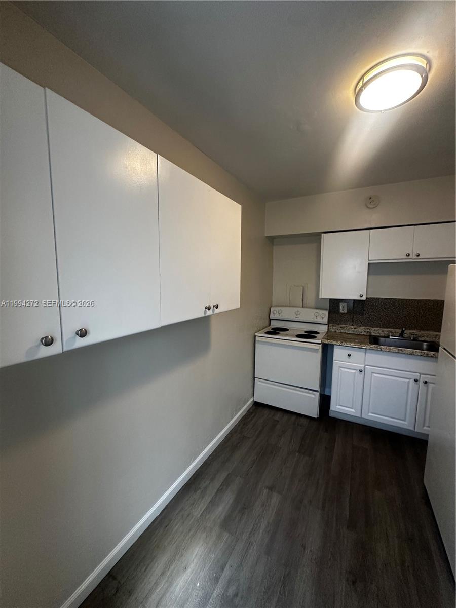 112 Northeast 63rd Street, Unit 112 Miami, FL 33138 - Photo 6 of 18 a kitchen with cabinets and wooden floor