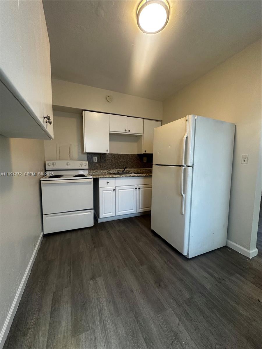 112 Northeast 63rd Street, Unit 112 Miami, FL 33138 - Photo 8 of 18 a kitchen with wooden floors and white appliances