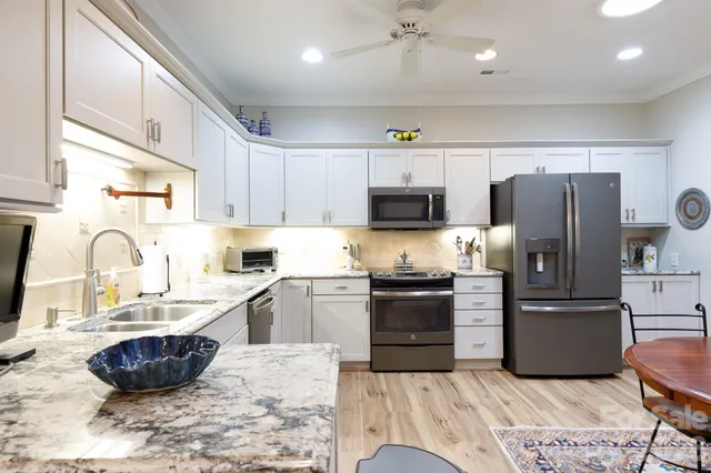 a kitchen with stainless steel appliances granite countertop a refrigerator sink and stove