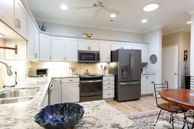 a kitchen with stainless steel appliances granite countertop a sink a stove a refrigerator cabinets and chairs