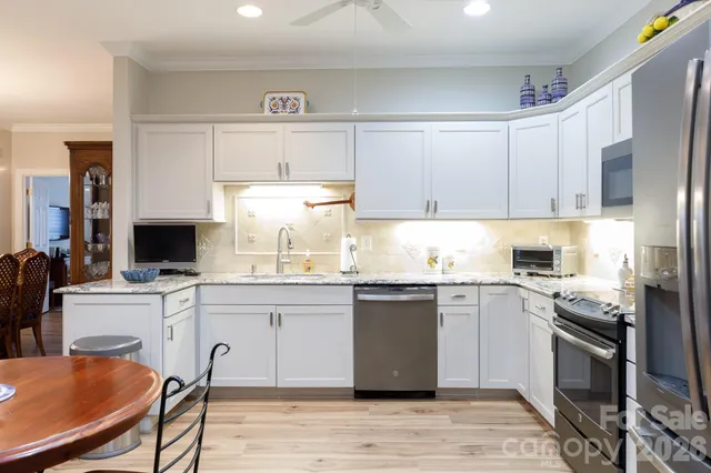 a kitchen with stainless steel appliances granite countertop a stove top oven a sink dishwasher and a refrigerator with wooden floor