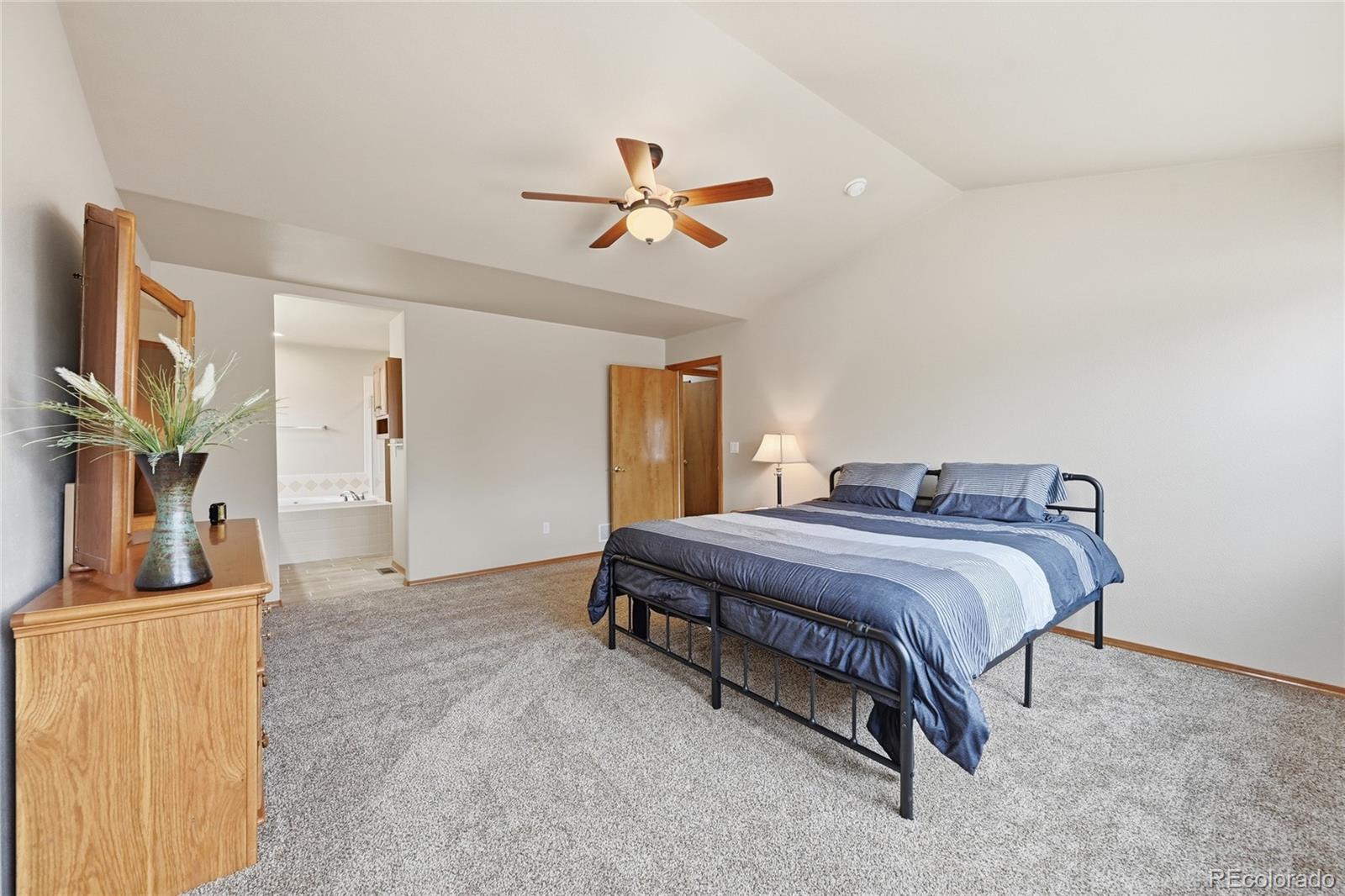9288 Rockingham Drive Peyton, CO 80831 - Photo 17 of 49 a spacious bedroom with a bed and a chandelier