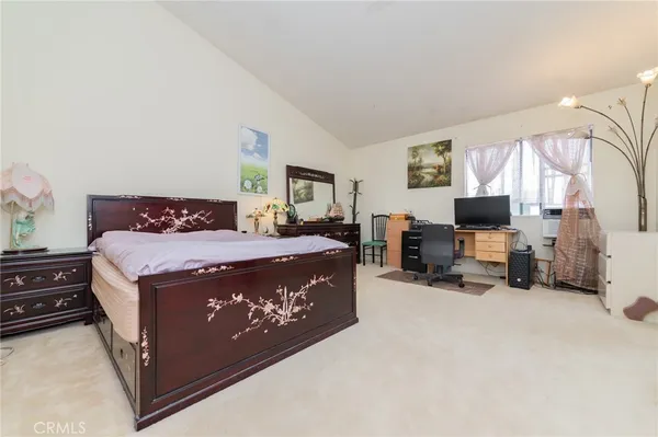 a bed sitting in a spacious bedroom next to a window and a flat screen tv