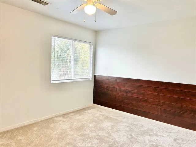 an empty room with a window and a fan