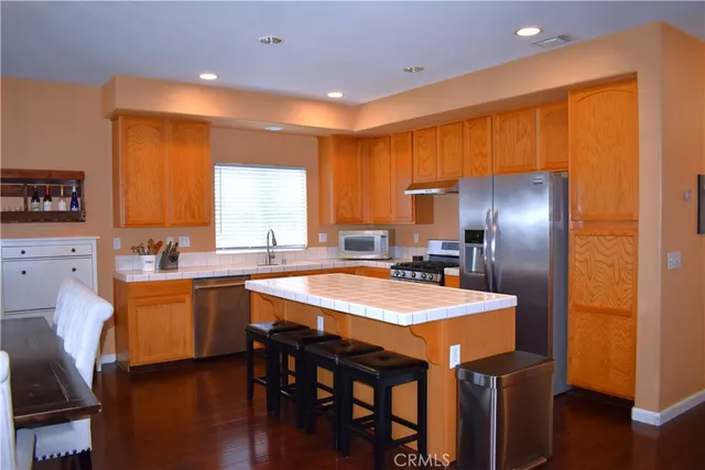 a kitchen with stainless steel appliances granite countertop a table chairs sink refrigerator and microwave