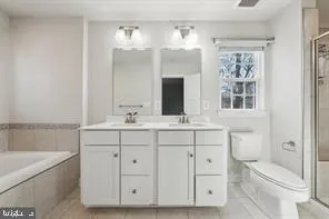 a bathroom with a double vanity sink a toilet and a bathtub