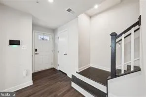 a view of front door with wooden floor and a ceiling fan
