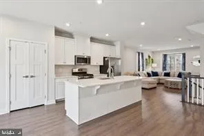a view of living room with kitchen island stainless steel appliances furniture cabinets and a center island