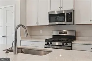 a kitchen with stainless steel appliances granite countertop a stove a microwave and a white cabinet