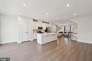 a view of kitchen with kitchen island stainless steel appliances wooden floor and living room view