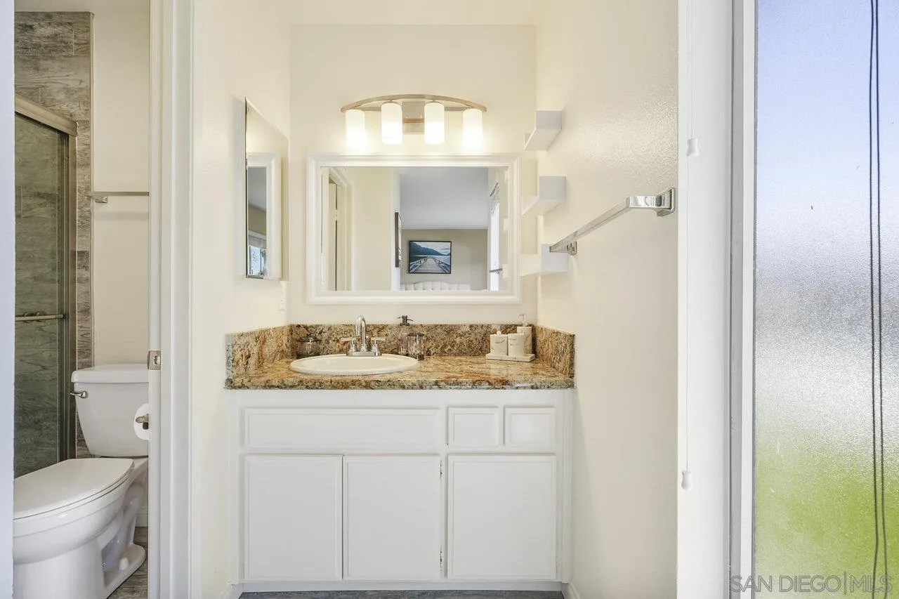 231 Blossom Way Oceanside, CA 92058 - Photo 16 of 31 a bathroom with a granite countertop sink and a mirror
