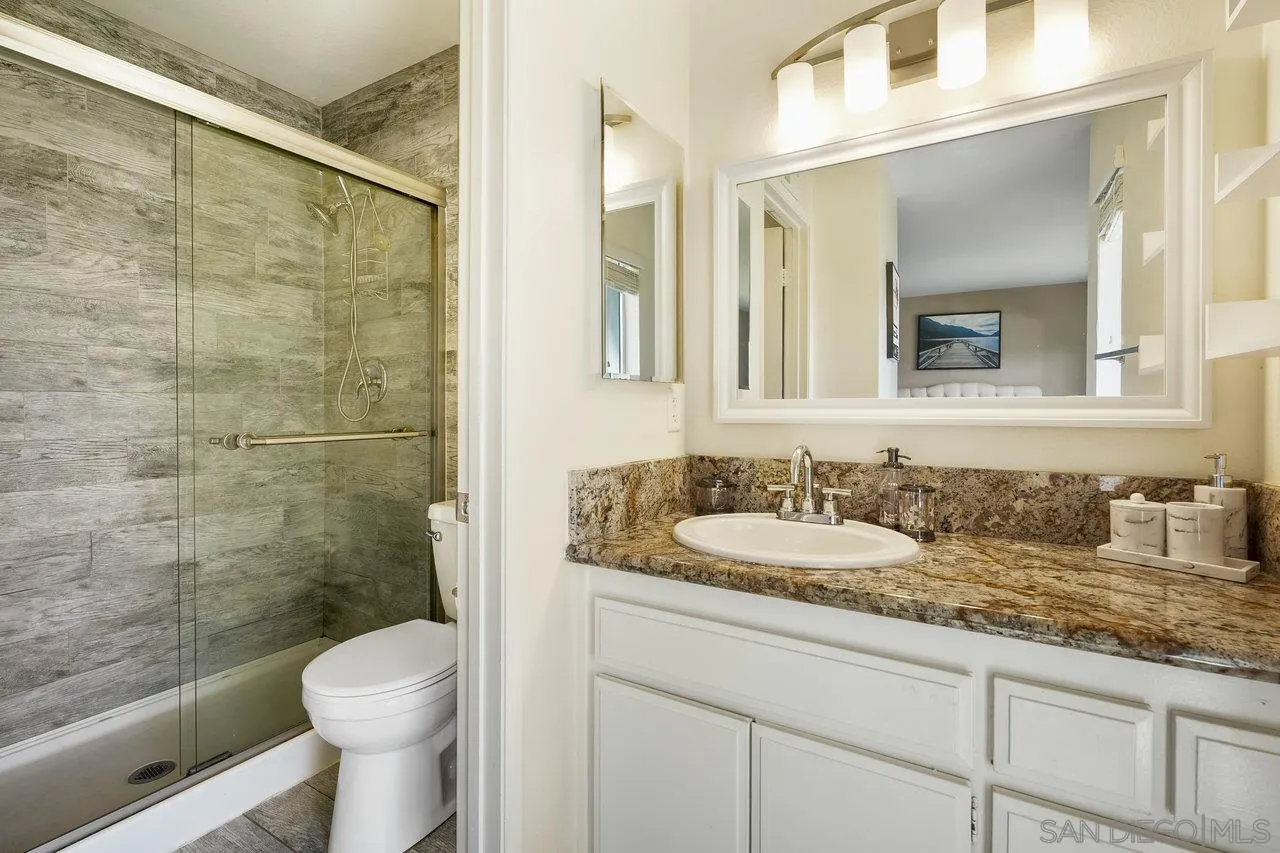 231 Blossom Way Oceanside, CA 92058 - Photo 17 of 31 a bathroom with a granite countertop sink a toilet a mirror and shower