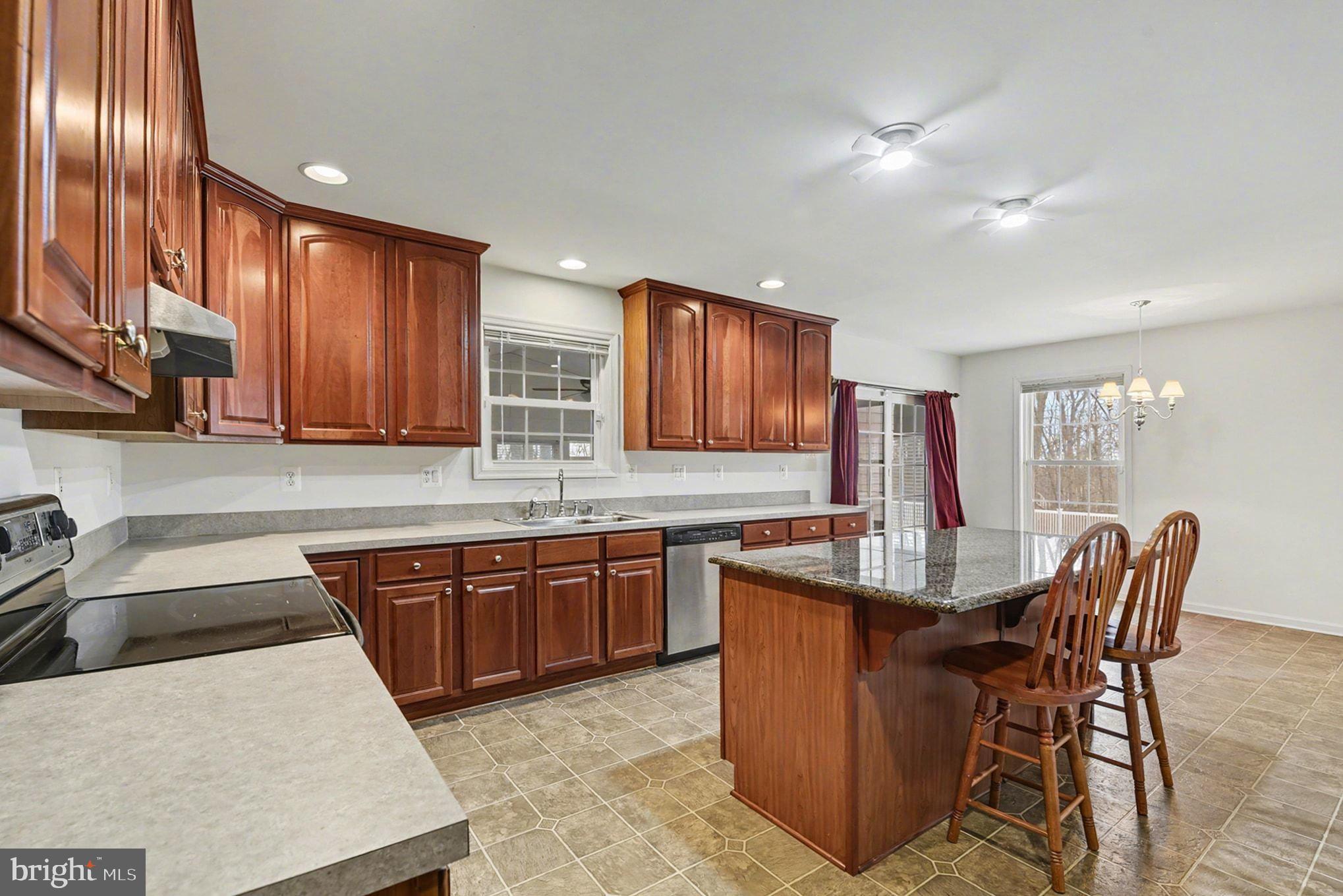 1645 Timber Summit Drive Westminster, MD 21157 - Photo 16 of 52 a kitchen with stainless steel appliances granite countertop a table chairs sink and cabinets