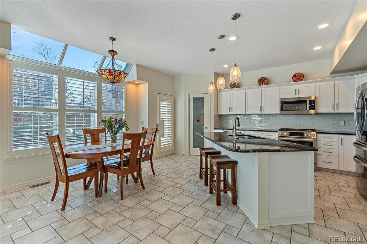 2290 Crestmont Lane Highlands Ranch, CO 80126 - Photo 9 of 40 a kitchen with stainless steel appliances a table chairs and a refrigerator