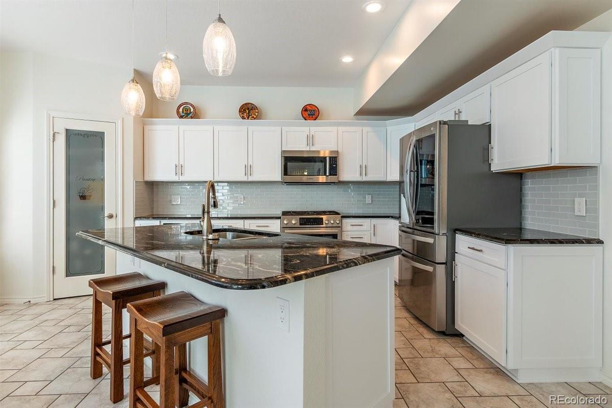 2290 Crestmont Lane Highlands Ranch, CO 80126 - Photo 10 of 40 a kitchen with stainless steel appliances granite countertop a sink stove and refrigerator