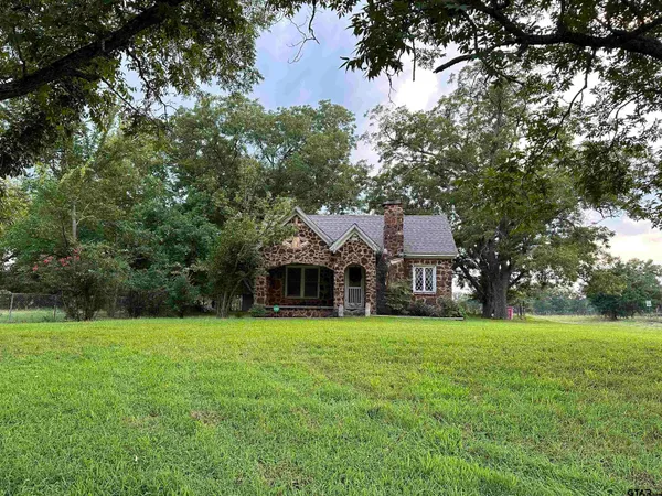 a view of a house with a big yard and large trees