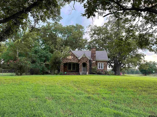 a view of a house with a big yard and large trees