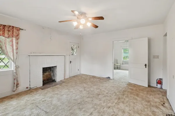 a view of an empty room with window and fireplace