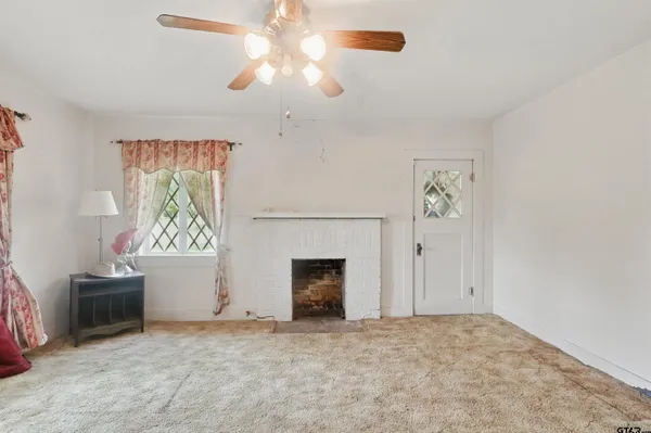 an empty room with windows and fireplace