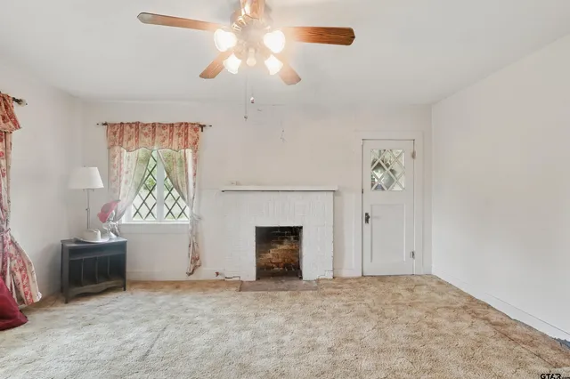 an empty room with windows and fireplace