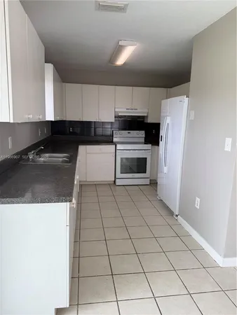 a kitchen with a sink a stove top oven and refrigerator