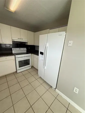 a kitchen with a sink a refrigerator and cabinets