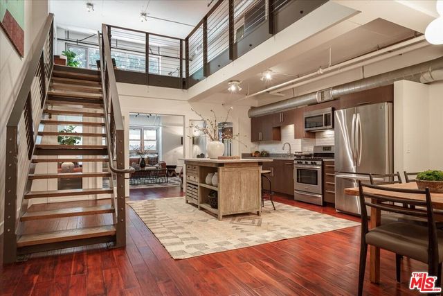 a kitchen with stainless steel appliances a stove a sink a microwave a refrigerator and white cabinets