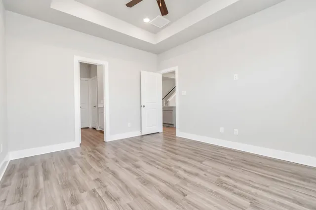 an empty room with wooden floor and ceiling fan