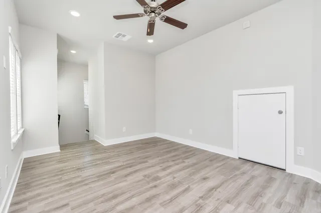 an empty room with wooden floor and a ceiling fan