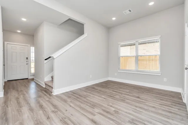 an empty room with wooden floor and windows