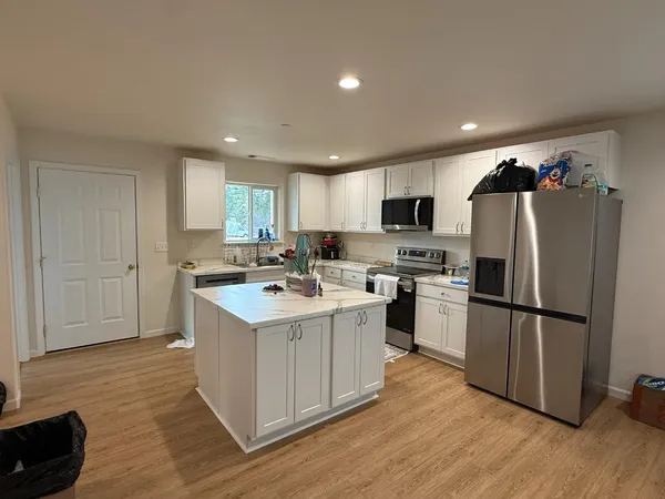 a kitchen with a refrigerator a sink dishwasher and a stove with wooden floor