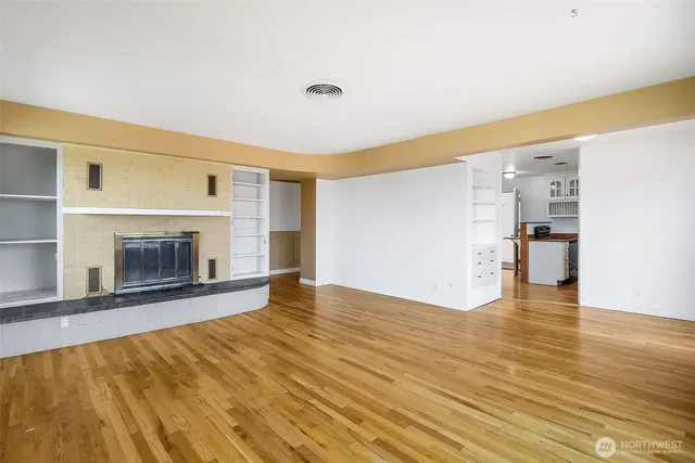 a view of empty room with wooden floor and a fireplace