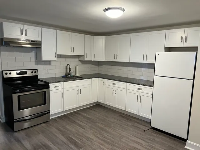 a kitchen with cabinets stainless steel appliances and wooden floor