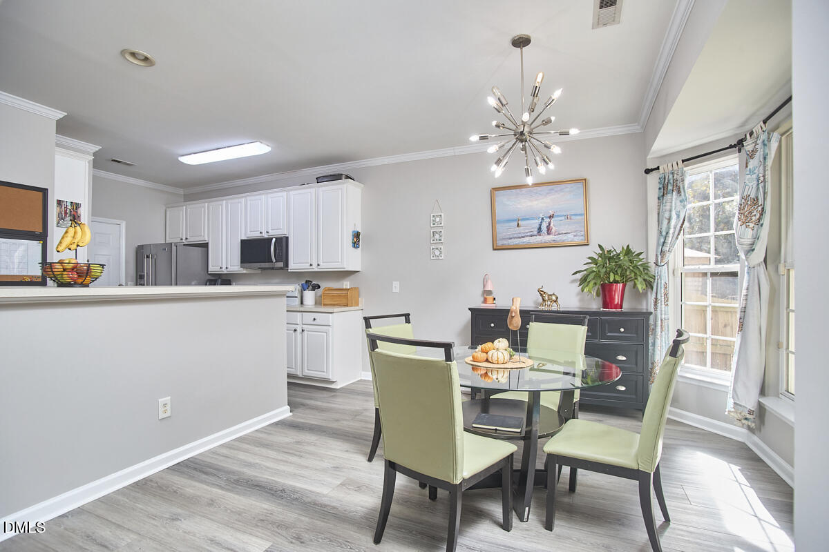 8441 Lunar Stone Place Raleigh, NC 27613 - Photo 19 of 43 a view of a dining room with furniture a chandelier and wooden floor