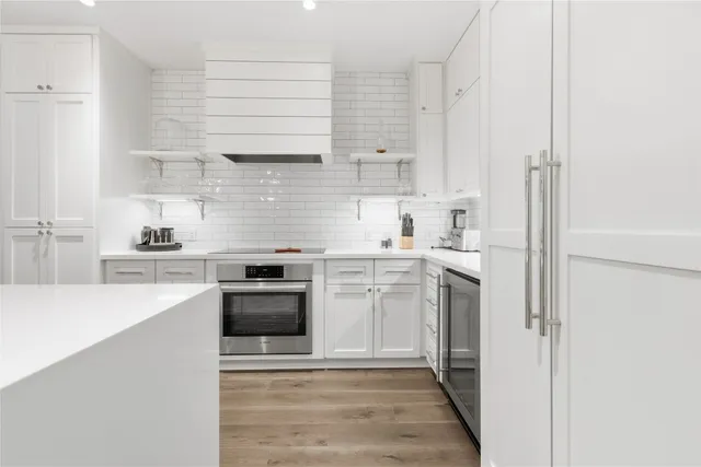 a view of a hallway with wooden floor and a bathroom