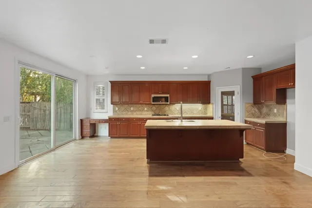 a large kitchen with a large counter top a sink stainless steel appliances and cabinets