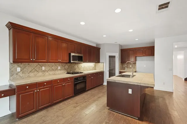 a large kitchen with stainless steel appliances granite countertop a sink dishwasher stove and wooden cabinets