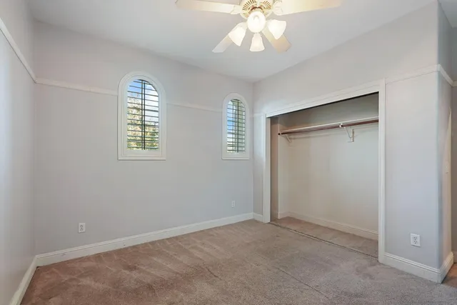 an empty room with windows and chandelier fan