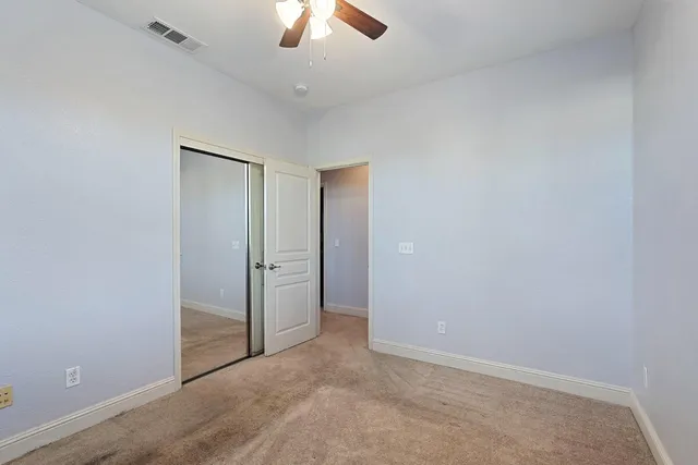 an empty room with ceiling fan and window