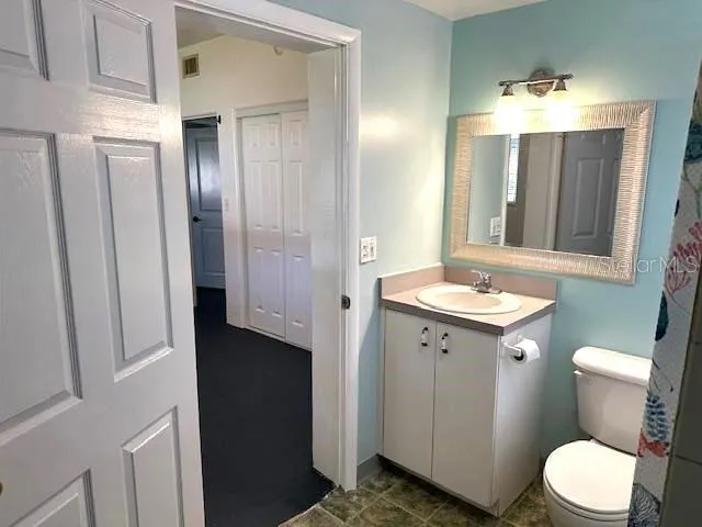 a bathroom with a granite countertop sink toilet and mirror