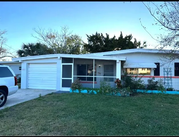 a view of a house with a yard and a large tree