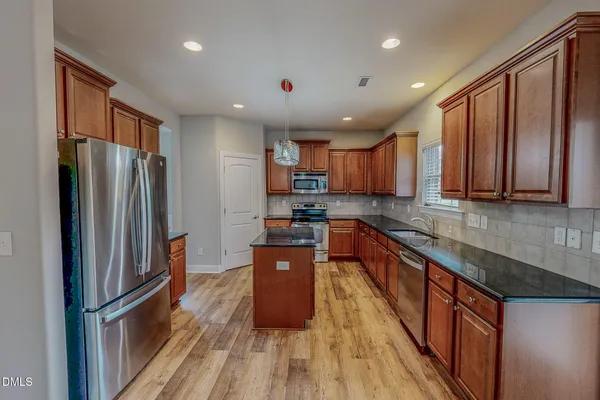 a kitchen with stainless steel appliances granite countertop refrigerator a sink dishwasher a stove top oven with wooden floor