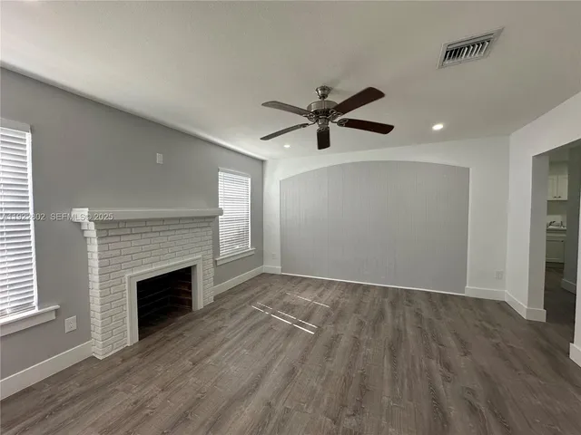 an empty room with wooden floor and a fireplace