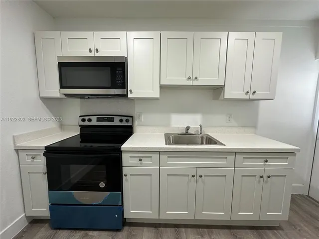 a kitchen with white cabinets and sink
