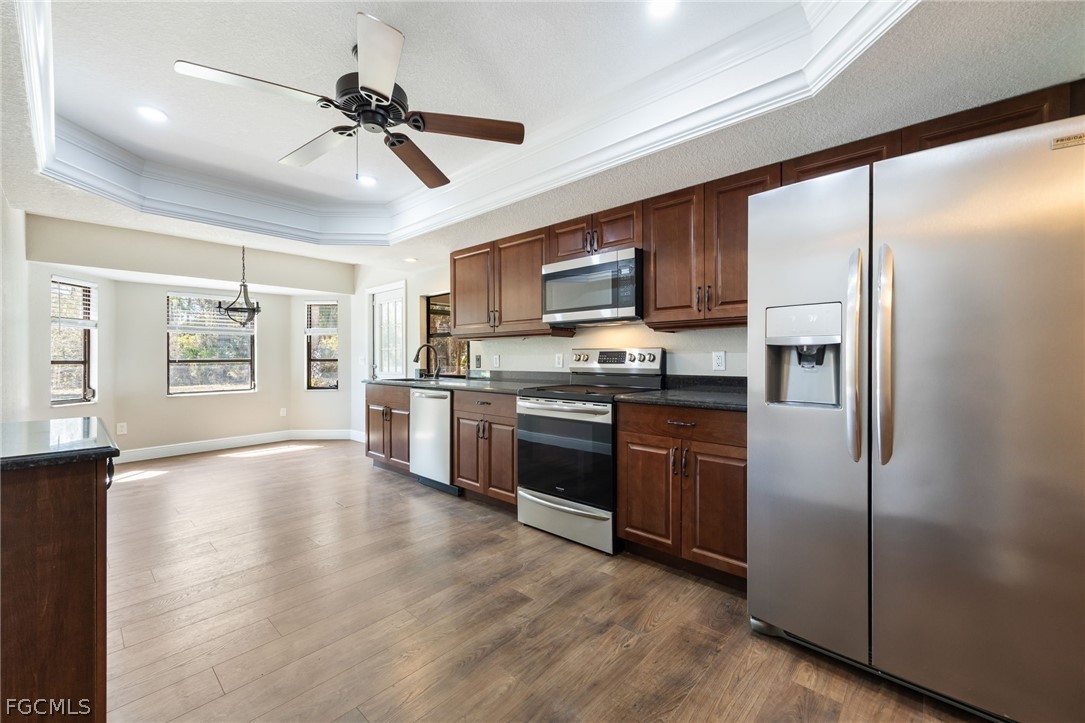 18890 Fox Run Road Alva, FL 33920 - Photo 9 of 50 a kitchen with stainless steel appliances granite countertop a refrigerator a stove top oven a sink with wooden floor and cabinets