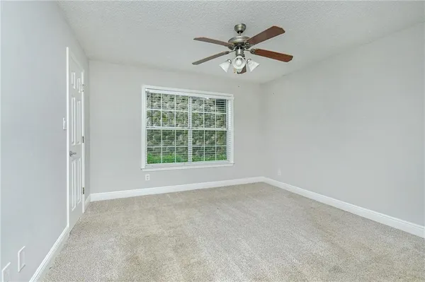 an empty room with window and ceiling fan