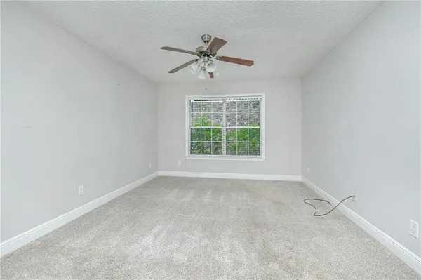 an empty room with a window and a ceiling fan