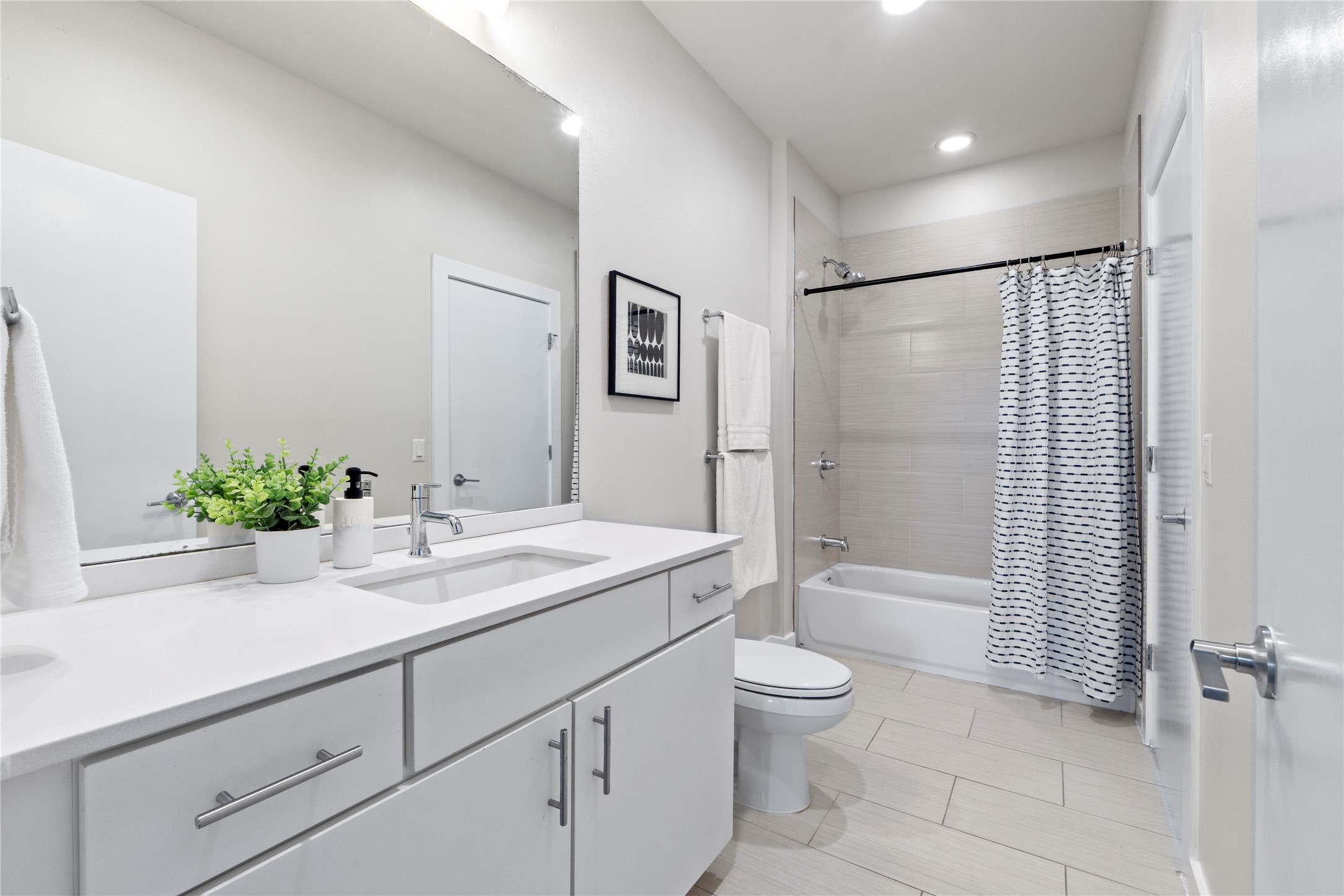 3001 Del Curto Road, Unit 35 Austin, TX 78704 - Photo 16 of 22 Bathroom featuring a vanity with a white countertop and an integrated sink, a large mirror, a toilet, and a bathtub with a shower and tiled surround